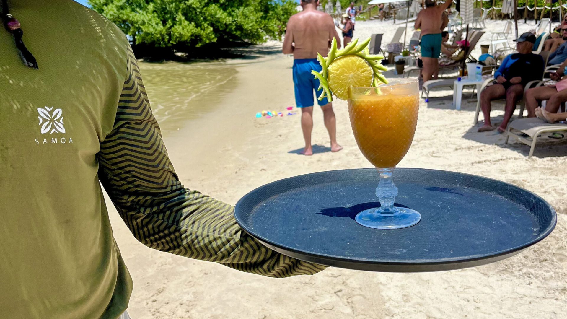 Garçom servindo drink autoral com apresentação no bar molhado.