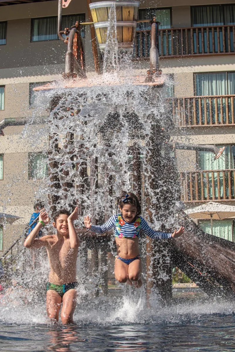 Crianças brincando sob o balde d'água na piscina infantil do Samoa Beach