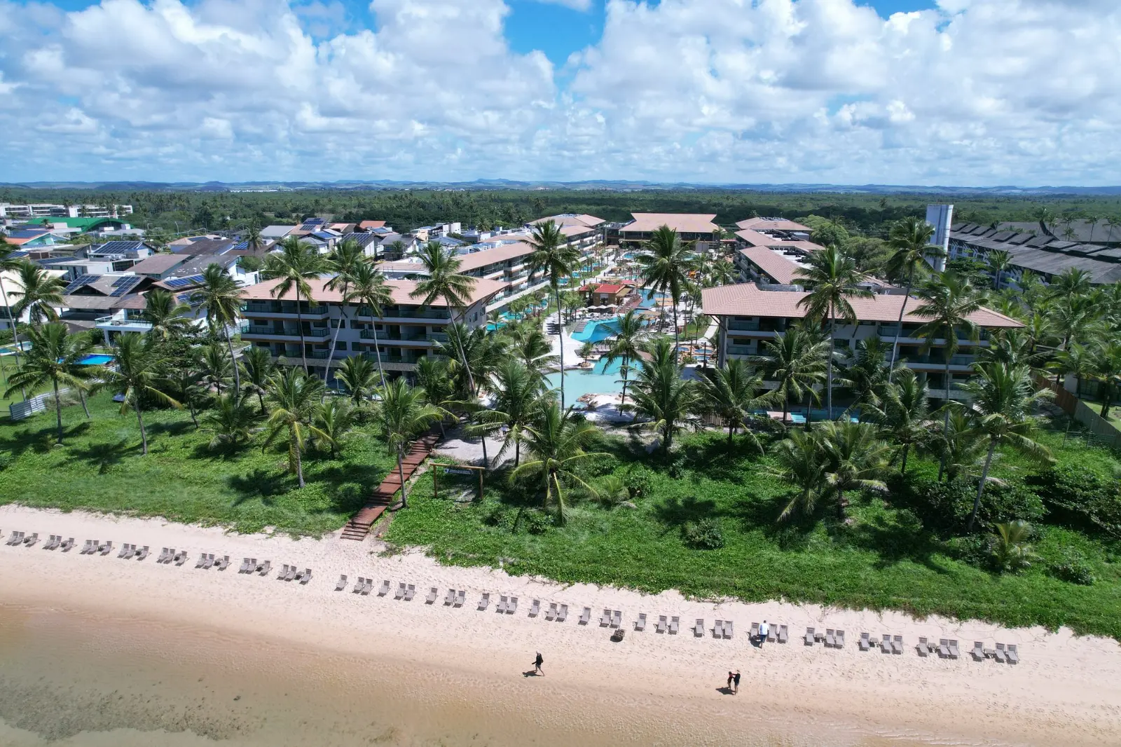 Vista aérea do Samoa Villa Resort entre coqueiros, de frente para a faixa de areia da Praia de Muro Alto